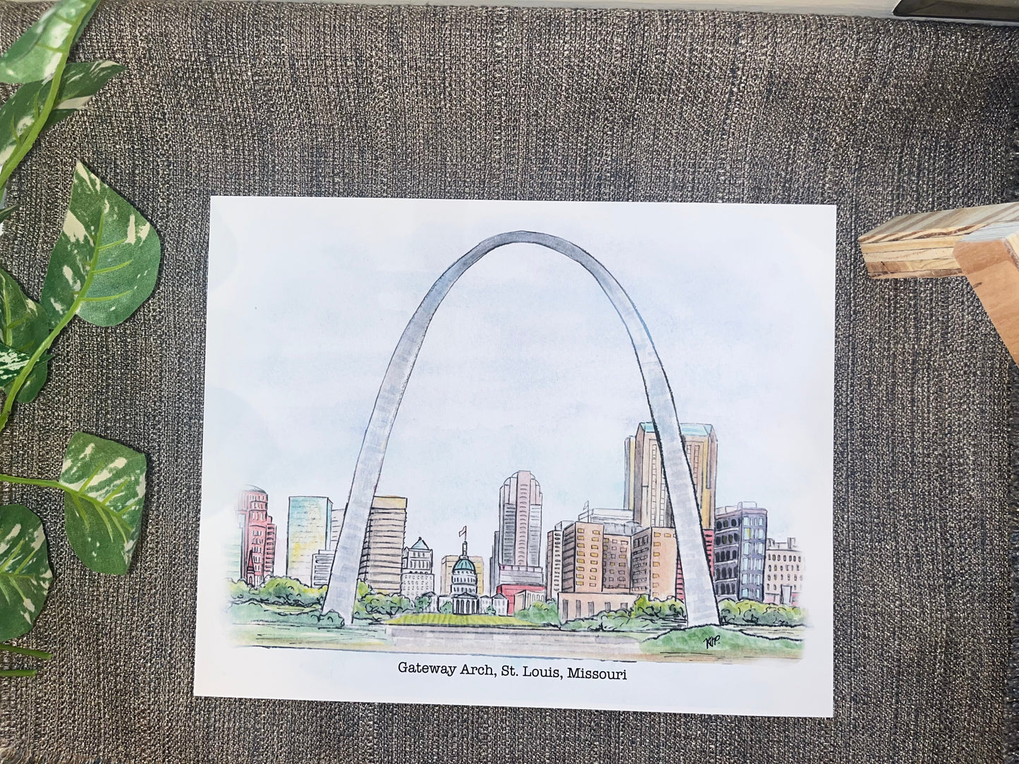 Illustration of the Gateway Arch in St. Louis, Missouri on a textured surface with leaves.